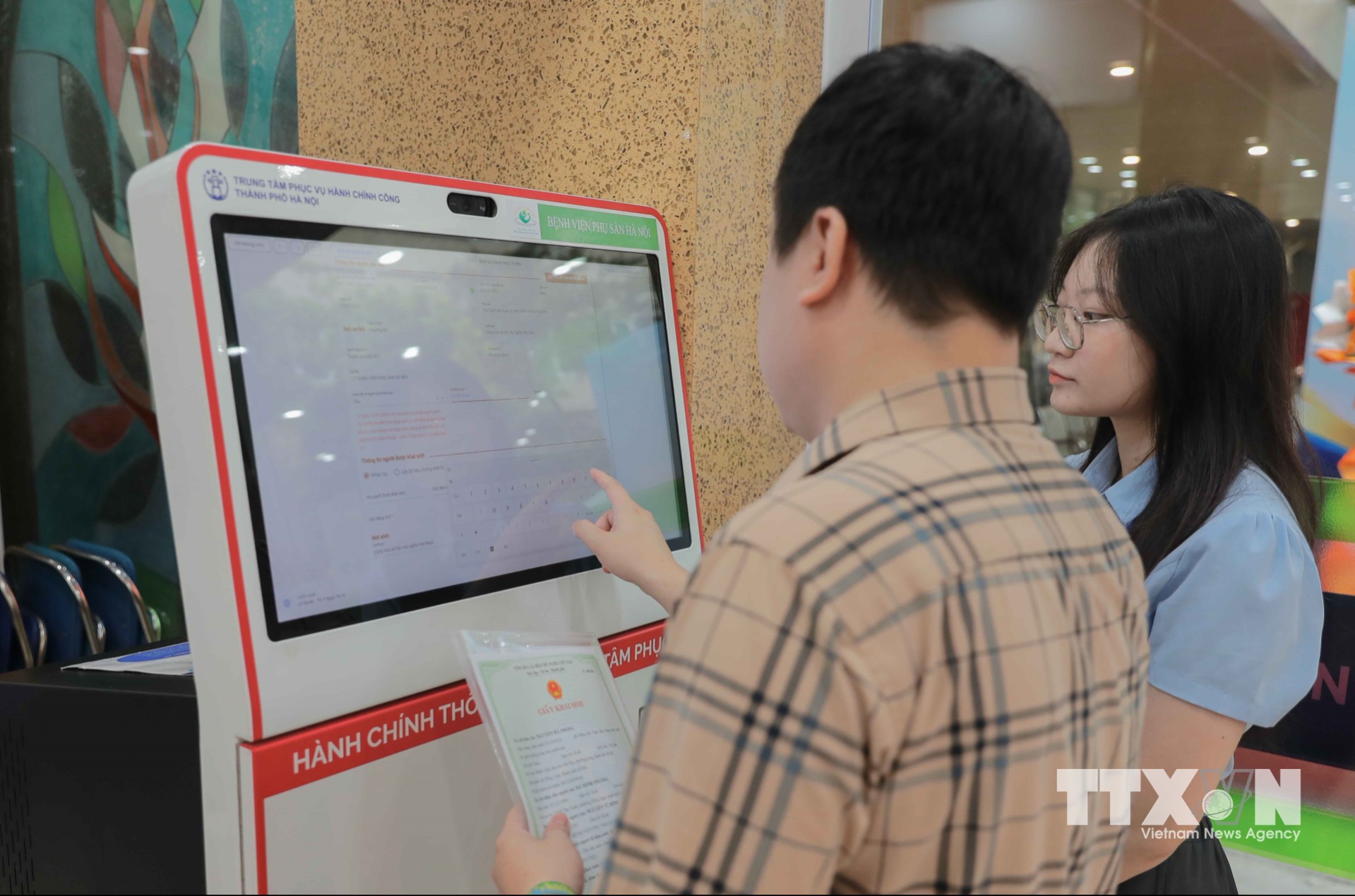 Cán bộ Trung tâm Phục vụ hành chính công thành phố Hà Nội hướng dẫn, giúp người dân không mất thời gian tìm hiểu, tiết kiệm thời gian đi lại, gia đình có thêm thời gian chăm sóc mẹ và bé khi chào đời. (Ảnh: Phan Phương/TTXVN)